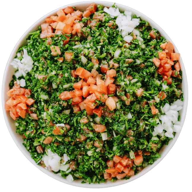 Tabouli Salad a chopped parsley mixed with diced tomatoes and onions in a white bowl