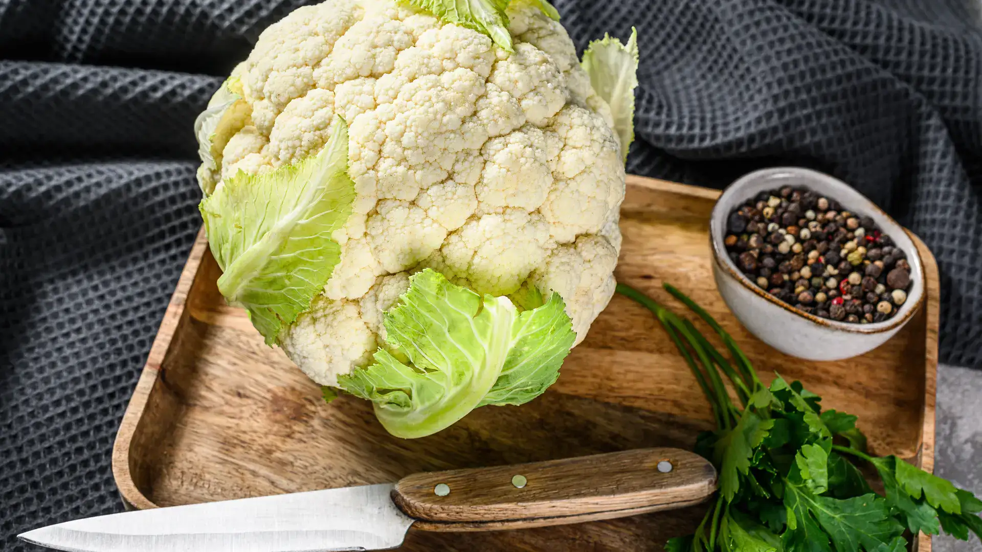 cauliflower on a cutting board with a knife and spices