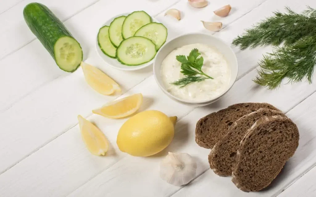 Traditional tzatziki dip with fresh cucumbers, dill, and olive oil, served alongside bread and lemon wedges.